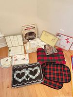 Overview of entire lot on floor: boxed linens, placemats, tea towels