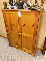 Frontal view of pine cabinet showing doors, knobs, base trim