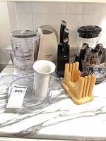 Overall lot showing food processor components, knife block with knives, blender base, bagel cutting guide