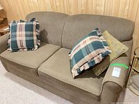 Front view of brown upholstered sofa with three throw cushions