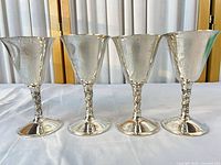 Set of four matching silver-plated cordial glasses standing side by side