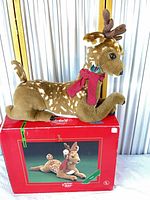 Full view of plush reindeer on top of original box