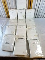 Front view of 12 sealed packages of white baby bodysuits
