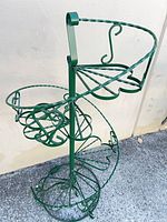 Full view of green spiral wrought iron plant stand showing tiers and scrollwork