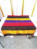 Full view of folded kilim rug on table showing multicolor stripes