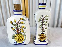 Front view of both ceramic bottles showing motifs and cork on left bottle