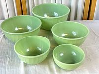 Five jadeite bowls nested on cloth showing set completeness