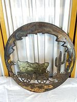 Full view of circular welded metal artwork with covered wagon scene