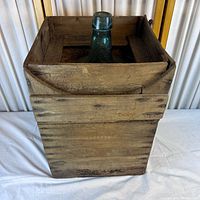 full view of wooden crate containing glass demijohn