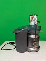 Breville juicer front view showing pulp container, clear lid, power cord