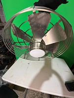 Front view of brushed nickel caged ceiling fan with integrated LED light and blades