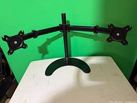 Front angled view showing dual arms, VESA plates and freestanding base