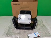 Front view of LED floodlight with side panels, remote, box