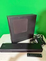 Soundbar, subwoofer, remote and power adapter on table