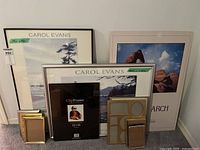 Two large framed posters with stack of assorted frames in front