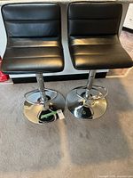Two black faux leather bar stools front view