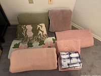 Group shot of all eight blankets including packaged Nicole Miller coverlet