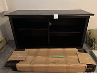 Front view of assembled black bookcase with boxed shelf visible