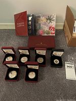 Overview showing seven boxed coins, three commemorative packs, gift boxes visible