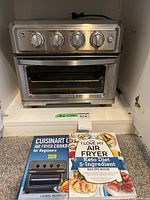 Oven with accessories and two cookbooks in cabinet