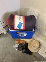 Group shot: cooler, sleeping bag, flashlight, hat, binoculars