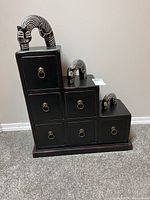 Front view of tiered chest with drawers and cat figures