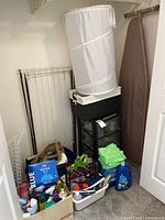 Closet view showing ironing board, hamper, storage drawers, cleaning supplies