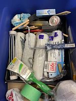 Close view of contents inside bin showing roller covers, brushes, tape, sanding block, paint tray