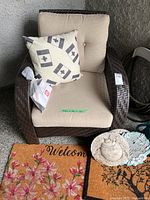 Armchair with cushions and pillow, mats and stones visible