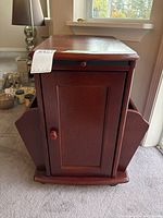 Front view of wooden side table showing cabinet door, knobs and side magazine racks