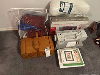 Group view of sewing machine, wooden sewing box, pillow form, fabric bag, binder