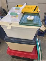 Stack of multiple plastic totes with lids, clear bin on top
