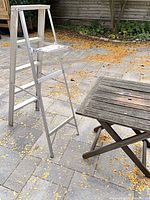 Full view of aluminum stepladder standing on patio