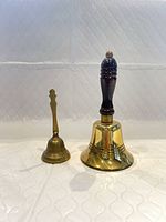 Front view of both brass hand bells showing size difference and handles