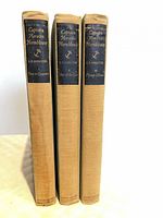 Spine view of three uniform tan cloth books with navy labels