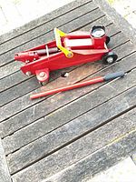 Top view of red hydraulic floor jack and handle
