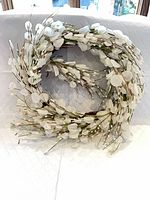 Full view of artificial white floral wreath on white background