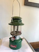 Front view of green Coleman Sportlite Model 335 lantern showing logo, pressure gauge and carry handle