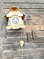 Full view of wooden cuckoo clock with weights and pendulum on wooden surface