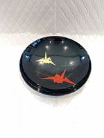 Top view of black plate with red and gold origami crane design