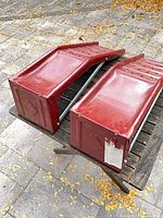 Pair of red steel car ramps on wooden table