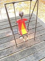 Front view of painted metal swinging lady sculpture