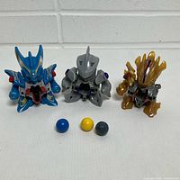 Front view of three B-Daman figures and three marbles