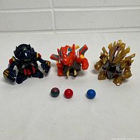 Front view of three B-Daman figures and three marbles