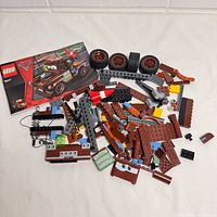 Spread of brown and grey Lego pieces, wheels, instruction booklet cover visible