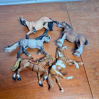 Five plastic horse figurines lying on side showing colours and underside