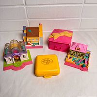 Five compact/building pieces arranged; shows overall lot contents including clear-domed building, house halves, pink bow compact, yellow compact