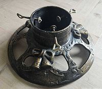 Oblique view of cast iron stand showing bell and bow motif and screw bolts