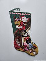 Front of stocking showing full needlepoint Santa scene and hanging loop