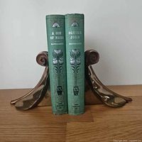 Front view of pair holding two green books